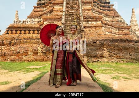 Junge asiatische Frauen in traditioneller thailändischer Kleidung gegen die Ruinen von Ayutthaya, der antiken Hauptstadt des Königreichs Siam. Ayutthaya, Thailand Mai 30, Stockfoto