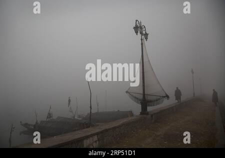 (181123) -- SRINAGAR, 23. November 2018 -- Fischer stehen am Ufer des Dal-Sees inmitten dichtem Nebel an einem kalten Morgen in Srinagar, der Sommerhauptstadt des von Indien kontrollierten Kaschmirs, 23. November 2018. Regen in den Ebenen und Schnee in den höheren Lagen werden wahrscheinlich im von Indien kontrollierten Kaschmir während der nächsten 24 Stunden auftreten, sagte ein Beamter der Meteorologie-Abteilung. ) KASCHMIR-SRINAGAR-WETTER JavedxDar PUBLICATIONxNOTxINxCHN Stockfoto