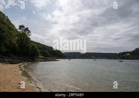 Blick entlang Small's Cove, East Portlemouth, nach Süden in Richtung Sunny Cove und die Sandbar mit Häusern rund um South Sands im Blick, große Wolke, ruhiges Wasser Stockfoto