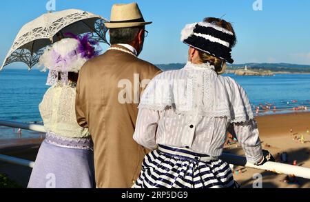 Zwei Frauen und ein Mann kleideten sich im viktorianischen Stil für die jährliche Banos de Ola-Veranstaltung Pquio Sardinero Santander Cantabria Spanien Stockfoto