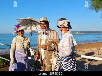 Zwei Frauen und ein Mann kleideten sich im viktorianischen Stil für die jährliche Banos de Ola-Veranstaltung Pquio Sardinero Santander Cantabria Spanien Stockfoto