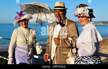 Zwei Frauen und ein Mann kleideten sich im viktorianischen Stil für die jährliche Banos de Ola-Veranstaltung Pquio Sardinero Santander Cantabria Spanien Stockfoto