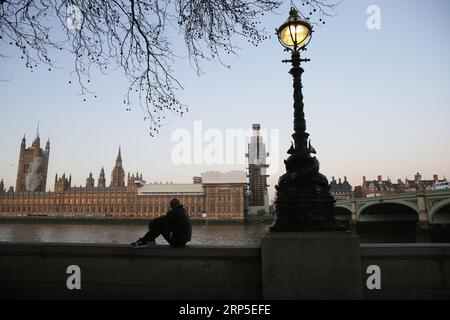 (181211) -- LONDON, 11. Dezember 2018 -- Ein Mann sitzt am Ufer der Themse mit den Houses of Parliament im Hintergrund in London, Großbritannien, am 11. Dezember 2018. Die britische Premierministerin Theresa May startete ihre Mission am Dienstag, um ihren Brexit-Deal mit einer Runde von Treffen mit den EU-Mitgliedern zu retten. ) GROSSBRITANNIEN-LONDON-BREXIT TimxIreland PUBLICATIONxNOTxINxCHN Stockfoto