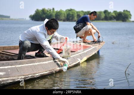 181220 -- CHANGSHA, 20. Dezember 2018 -- Geng Mingming L, ein wissenschaftlicher Mitarbeiter, nimmt eine Probe des Seenwassers im Gebiet Dongting Lake Area, Provinz Hunan in Zentralchina, 25. August 2018. Das Sammeln von Boden im Frühjahr, das Testen von Seenwasser im Sommer, die Untersuchung von Pflanzen im Herbst und die Beobachtung von Zugvögeln im Winter umrissen fast zehn Jahre saisonalen Zyklus des täglichen Lebens namenloser wissenschaftlicher Forscher im Gebiet des Dongting Lake. Sie haben hart daran gearbeitet, Lösungen für den Schutz der Umwelt und der biologischen Vielfalt zu finden. Die wissenschaftlichen Forscher der Chinesischen Akademie der Wissenschaften CAS waren es Stockfoto