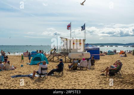 Bournemouth, Großbritannien - 1. September 2023: Menschen sitzen am Strand rund um den Wachturm RNLI. Stockfoto