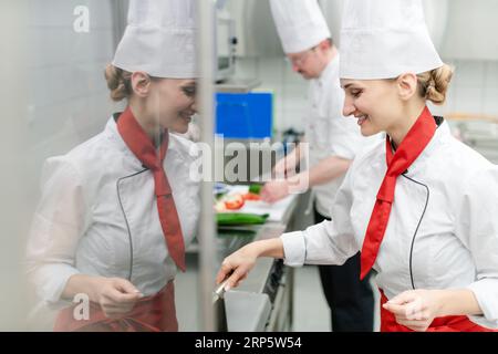 Köche in großen kommerziellen Küche kochen Mahlzeiten zusammen Stockfoto