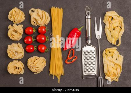 Bio-Lebensmittel auf schwarzem Hintergrund. Verschiedene Arten und Formen trockener italienischer Pasta mit Gemüse, Tomaten, Paprika, Knoblauch, Petersilie. Reibe und Stockfoto