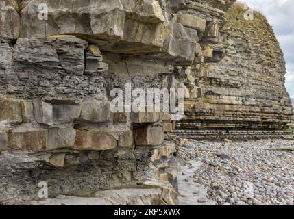 Diese Klippe an einem walisischen Strand zeigt, was die Auswirkungen der Küstenerosion und des Wetters im Laufe der Zeit auf die Felsschichten, die ihn stützen, bewirken können. Stockfoto