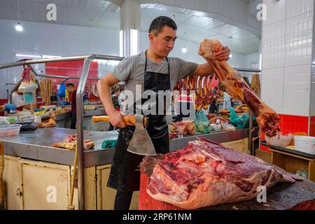 Bischkek, Kirgisistan - 2. September 2023: Ein Mann, der Fleisch im Osch-Basar in Bischkek, Kirgisistan, verkauft. Stockfoto