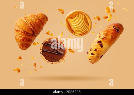 Frisch gebackenes Croissant und süßes Gebäck fliegen in die Luft. Süße Nachspeise. Backwaren. Stockfoto