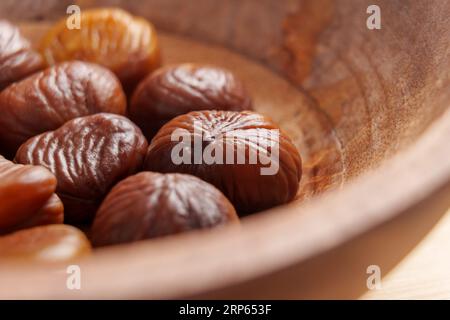 Gekochte Kastanienfrüchte mit Schale in einer Holzschale. Makro Stockfoto