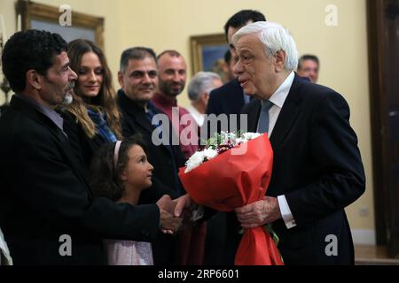 (190103) -- ATHEN, 3. Januar 2019 -- der griechische Präsident Prokopis Pavlopoulos (1. R) trifft sich und gratuliert drei Fischern und ihren Familien in der Präsidentenvilla in Athen, Griechenland, 2. Januar 2019. Die Ägypter Emand El Khamisi (50), Mahmoud Moussa (46) und der Albaner Jeka Gani (35) riskierten am 23. Juli 2018 neben vielen anderen einheimischen Fischern ihr Leben und retteten Dutzende von Menschen, die vor der Flamme flohen, die durch den Badeort Mati, etwa 30 Kilometer nordöstlich von Athen, fegte. Hundert Menschen starben an diesem Abend in den Flammen oder im Meer. Der griechische Präsident Prokopis Pavlopoulos unterzeichnete einige d Stockfoto