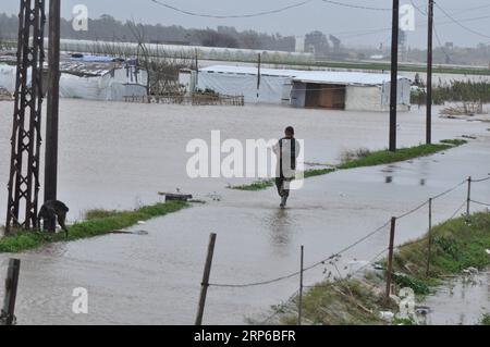 (190108) -- BEIRUT, 8. Januar 2019 (Xinhua) -- Ein Flüchtling geht im Hochwasser in einem syrischen Flüchtlingslager am Rande von Tripoli, Libanon, 8. Januar 2019. Die syrischen Flüchtlinge, die in Zelten im Libanon leben, haben mehr gelitten, da ein großer Sturm, genannt Norma, in vielen Gebieten des Landes schwere Schäden verursacht. (Xinhua/Khalid) LIBANON-TRIPOLI-WETTEREXTREME-SYRISCHE FLÜCHTLINGE PUBLICATIONxNOTxINxCHN Stockfoto