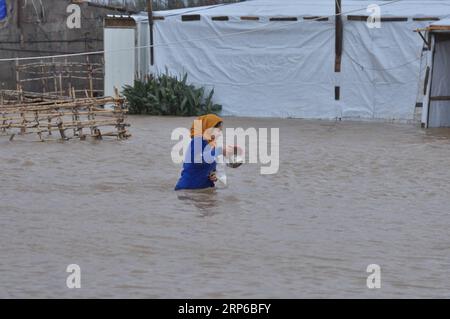 News Bilder des Tages (190108) -- BEIRUT, 8. Januar 2019 (Xinhua) -- Eine Flüchtlingsfrau geht im Hochwasser in einem syrischen Flüchtlingslager am Rande von Tripoli, Libanon, 8. Januar 2019. Die syrischen Flüchtlinge, die in Zelten im Libanon leben, haben mehr gelitten, da ein großer Sturm, genannt Norma, in vielen Gebieten des Landes schwere Schäden verursacht. (Xinhua/Khalid) LIBANON-TRIPOLI-WETTEREXTREME-SYRISCHE FLÜCHTLINGE PUBLICATIONxNOTxINxCHN Stockfoto