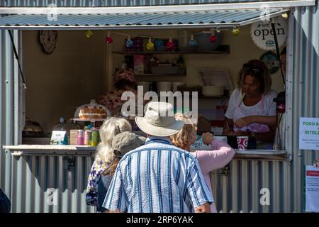 Kunden, die auf einer Veranstaltung in einem Tee- und Kuchenwagen warten. Catering-Caravan mit Tee, Kaffee und Kuchen. Stockfoto