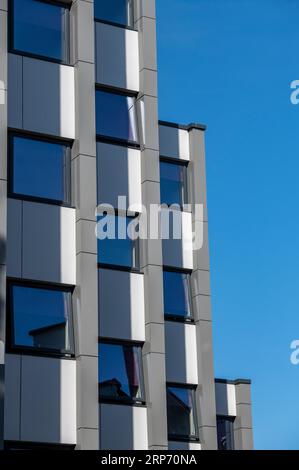 Abstrakter moderner Wohnblock mit verschiedenen Etagen oder Ebenen und blauem Himmelshintergrund. Stockfoto