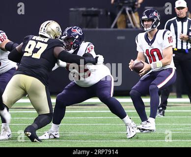 New Orleans, USA. 27. August 2023. Houston Texans Quarterback Davis Mills (10) fällt zurück, während der Wärter Kenyon Green (59) die New Orleans Saints Defensive End Malcolm Roach (97) während eines Vorbereitungsspiels der National Football League im Caesars Superdome in New Orleans, Louisiana, am Sonntag, den 27. August 2023 blockiert. (Foto: Peter G. Forest/SIPA USA) Credit: SIPA USA/Alamy Live News Stockfoto