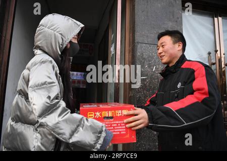 (190203) -- XI AN, 3. Februar 2019 (Xinhua) -- Lieferer Luo Feilong (R) übergibt ein Paket an einen Kunden in Xi an, Hauptstadt der nordwestchinesischen Provinz Shaanxi, 3. Februar 2019. Luo Feilong, ein 31-jähriger Lieferer aus der Provinz Shaanxi, liefert seit vier Jahren Pakete in einer Gemeinde von Xi an. Luo bewarb sich während des diesjährigen Frühlingsfests um Dienstbereitschaft, damit andere Helfer aus der Provinz zu Familientreffen in ihre Heimatorte zurückkehren können. (Xinhua/Zhang Bowen) CHINA-XI AN-SPRING FESTIVAL-DELIVERYMAN (CN) PUBLICATIONxNOTxINxCHN Stockfoto