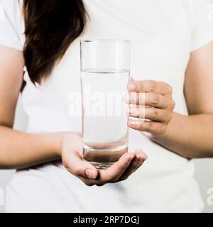 Die weiblichen Hände mit Glaswasser beschneiden Stockfoto