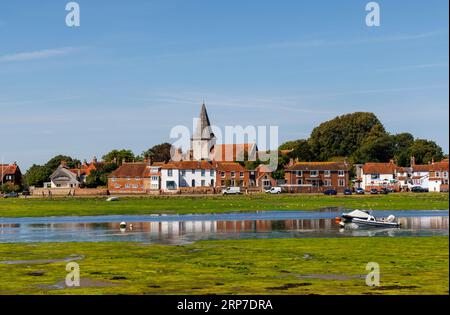 Blick auf die Holy Trinity Kirche und die Gezeitenwohnungen in Bosham, einem Küstendorf an der Südküste von Chichester Harbour, West Sussex, bei Ebbe Stockfoto