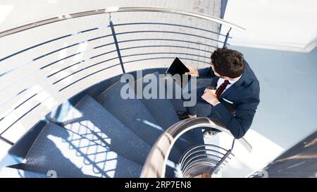 Mann mit Blick von oben und Tablet, Treppen stehen Stockfoto