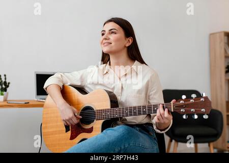 Vorderansicht Smiley weibliche Musikerin, die akustische Gitarre spielt Stockfoto