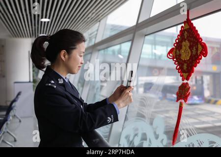 (190207) -- QINGDAO, 7. Februar 2019 (Xinhua) -- Policewoman Feng Zhe spricht mit ihrem Sohn über einen Videoanruf während einer Pause an der Einwanderungskontrollstelle des Flughafens in Qingdao, ostchinesische Provinz Shandong, 6. Februar 2019. Polizeibeamte an der Grenzkontrollstelle des Flughafens in Qingdao waren wie üblich während des chinesischen Mondneujahrs im Dienst. (Xinhua/Xie Hao) CHINA-QINGDAO-SPRING FESTIVAL-POLICE (CN) PUBLICATIONxNOTxINxCHN Stockfoto