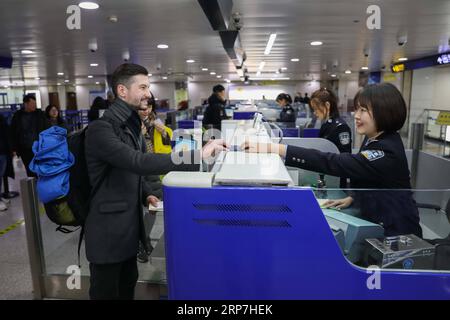 (190207) -- QINGDAO, 7. Februar 2019 (Xinhua) -- die Polizistin Wang Qian (R) hilft einem Ausländer, an der Einwanderungskontrollstelle des Flughafens in Qingdao, der ostchinesischen Provinz Shandong, am 6. Februar 2019 freigelassen zu werden. Polizeibeamte an der Grenzkontrollstelle des Flughafens in Qingdao waren wie üblich während des chinesischen Mondneujahrs im Dienst. (Xinhua/Xie Hao) CHINA-QINGDAO-SPRING FESTIVAL-POLICE (CN) PUBLICATIONxNOTxINxCHN Stockfoto