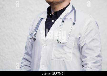 Nahaufnahme eines männlichen Arztes mit Stethoskop um den Hals vor weißem Hintergrund Stockfoto