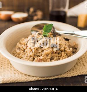 Köstliche weiße Schüssel mit Pilzrisotto und Löffel Stockfoto