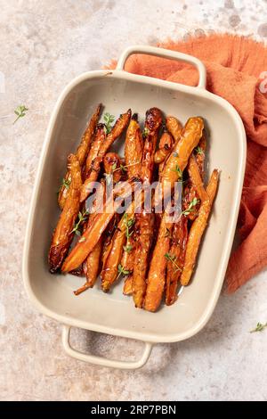 Geröstete Karotten mit Thymian, Knoblauch, Zitrone und Honig auf Backblech. Gesundes Wurzelgemüse-Konzept Stockfoto