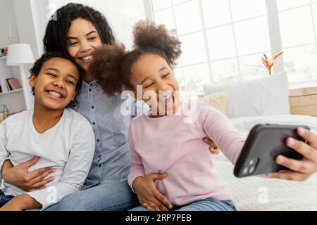 Lächelnde Mutterkinder nehmen Selfie mit nach Hause Stockfoto