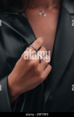 Nahaufnahme von modischen Details einer schwarzen Lederjacke und silbernen Ring-Accessoires. Schickes Outfit, Accessoires für Frauen Stockfoto