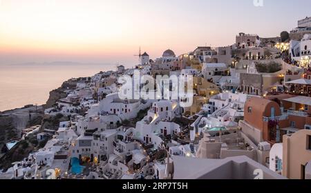 Häuser an den Klippen, Villen und Windmühle im Dorf Oia, Ia, vom Schloss Kasteli, Santorin, Griechenland aus gesehen Stockfoto