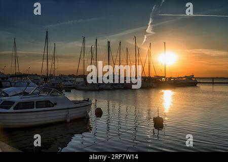 Sonnenuntergang über dem Yachthafen im Sommer. Silhouetten von Yachten gegen den Himmel mit der untergehenden Sonne. Stockfoto