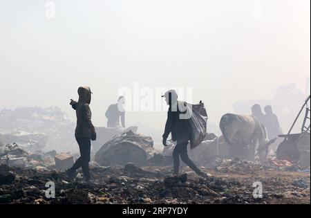 Gaza, Palästina. September 2023. Die Menschen durchsickern Müll an einer Deponie, während Rauch von einem Feuer auf der Deponie östlich von Gaza-Stadt ausgeht. Die größte Mülldeponie fing aufgrund hoher Temperaturen und hoher Windgeschwindigkeiten Feuer an, und palästinensische Feuerwehrfahrzeuge stürzten aus, damit sie sich nicht auf Wohnviertel ausbreiteten. Quelle: SOPA Images Limited/Alamy Live News Stockfoto