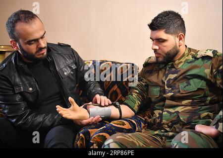 (190220) -- HAMA, 20. Februar 2019 -- Ali Bakeer (L) installiert am 18. Februar 2019 eine Prothesenhand, die er für einen amputierten Militäroffizier in Rabia in der Provinz Hama, Zentralsyrien, geschaffen hat. Ali Bakeer, ein Medizinstudent in Syrien, hat eine Handprothese entwickelt, die behinderten Menschen helfen soll, die während des Krieges verletzt wurden. Der 22-jährige Student Rabia in der zentralen Provinz Hama sagte, dass er schon als Junge ein starkes Interesse an Elektronik habe. Die Idee der Herstellung der Handprothese wurde von den Bedürfnissen der Verletzten während der angetrieben Stockfoto