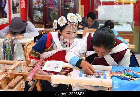 (190221) -- LIJIANG, 21. Februar 2019 (Xinhua) -- Fan Yongzhen(L, Front), Abgeordneter des 13. Nationalen Volkskongresses Chinas (NPC), führt am 13. Februar 2019 in der Baisha-Altstadt des autonomen Komitats Yulong Naxi in Lijiang, Provinz Yunnan, eine Forschung über Dianxiu-Stickereien durch. Als stellvertretende Kuratorin des Kulturzentrums in Lijiang hat sich Fan der Karriere des Schutzes und der Förderung lokaler ethnischer Kulturen verschrieben. Außerdem leistet sie einen Beitrag zur Massenkultur, indem sie gemeinsam mit ihren Kollegen Performances in ländliche Gebiete schickt. Als Stellvertreter des NPC, Chi Stockfoto