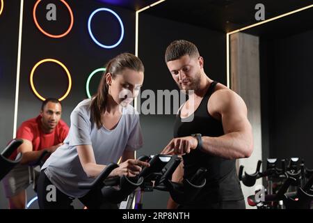 Trainer, der mit Menschen im Fitnessclub arbeitet. Indoor-Radkurs Stockfoto