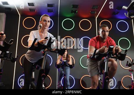 Gruppe von Personen, die im Fitnessklub auf Fahrrädern trainieren Stockfoto