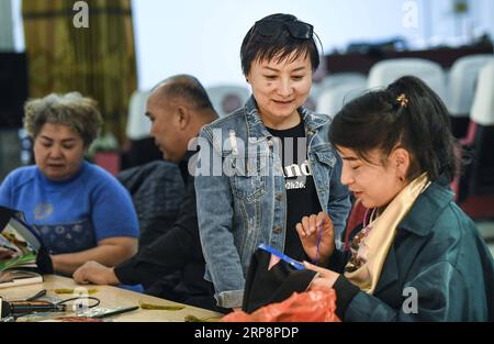 (190313) -- HAMI, 13. März 2019 (Xinhua) -- Renagul (2. R) diskutiert Sticktechniken mit Aygul Iskender (1. R) auf ihrem Workshop im Bezirk Yizhou der Stadt Hami, nordwestchinesische Autonome Region Xinjiang Uygur, am 8. März 2019. Die Haute Couture, wörtlich Blossoming Flower genannt, mit handgefertigten Stickereien mit unverwechselbarem lokalem Geschmack verziert, wurde 2016 auf der Pariser Fashion Week präsentiert. Diese veränderte das Leben der Stickerin Renagul, die nie dachte, dass ihre Werke auf einer weltberühmten Modenschau gezeigt werden würden. Renagul wuchs in einer Stickereifamilie in Hami auf. Beeinflusst von ihrem Mo Stockfoto