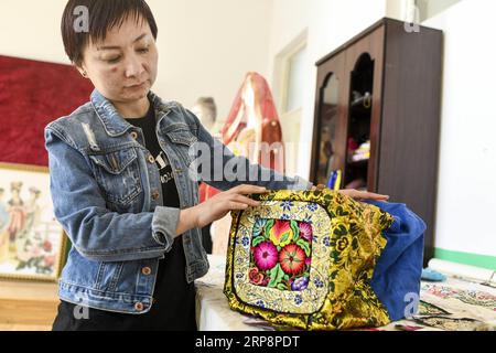 (190313) -- HAMI, 13. März 2019 (Xinhua) -- Renagul arrangiert ihre Stickprodukte am 8. März 2019 in ihrer Werkstatt im Bezirk Yizhou der Hami-Stadt, nordwestchinesische Autonome Region Xinjiang Uygur. Die Haute Couture, wörtlich Blossoming Flower genannt, mit handgefertigten Stickereien mit unverwechselbarem lokalem Geschmack verziert, wurde 2016 auf der Pariser Fashion Week präsentiert. Diese veränderte das Leben der Stickerin Renagul, die nie dachte, dass ihre Werke auf einer weltberühmten Modenschau gezeigt werden würden. Renagul wuchs in einer Stickereifamilie in Hami auf. Von ihrer Mutter beeinflusst, stickt sie gerne Stockfoto