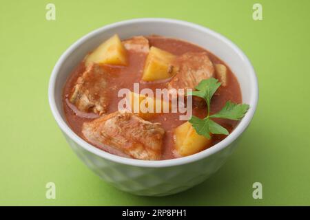 Köstliches Gulasch in der Schüssel auf grünem Hintergrund Stockfoto