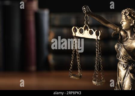 Symbol der gerechten Behandlung nach dem Gesetz. Statue von Lady Justice in der Nähe von Büchern auf dem Tisch, Nahaufnahme mit Platz für Text Stockfoto