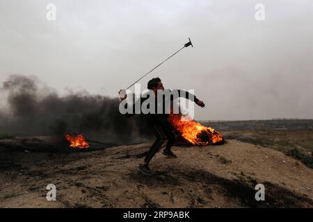 (190330) -- GAZA, 30. März 2019 -- Ein palästinensischer Demonstrant schleudert mit einer Schleuder Steine auf israelische Truppen während der Auseinandersetzungen an der Grenze zwischen Gaza und Israel, östlich von Gaza-Stadt, 30. März 2019. Tausende Palästinenser feierten am Samstag den palästinensischen Landtag und den ersten Jahrestag des großen palästinensischen Rückkehrmarsches. Stringer) MIDEAST-GAZA-KONFLIKTE ZhaoxYue PUBLICATIONxNOTxINxCHN Stockfoto