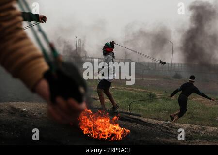 (190330) -- GAZA, 30. März 2019 -- Ein palästinensischer Demonstrant schleudert mit einer Schleuder Steine auf israelische Truppen während der Auseinandersetzungen an der Grenze zwischen Gaza und Israel, östlich von Gaza-Stadt, 30. März 2019. Tausende Palästinenser feierten am Samstag den palästinensischen Landtag und den ersten Jahrestag des großen palästinensischen Rückkehrmarsches. Stringer) MIDEAST-GAZA-KONFLIKTE ZhaoxYue PUBLICATIONxNOTxINxCHN Stockfoto