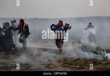 (190330) -- GAZA, 30. März 2019 () -- Ein palästinensischer Sanitäter trägt einen verwundeten Jungen bei Zusammenstößen mit israelischen Truppen an der Grenze zwischen Gaza und Israel, östlich von Gaza-Stadt, 30. März 2019. Mindestens drei Palästinenser wurden am Samstag bei einem tagelangen Zusammenstoß mit israelischen Soldaten im östlichen Gazastreifen nahe der Grenze zu Israel getötet und 316 verletzt, sagten Mediziner. Die heftigen Zusammenstöße markierten den ersten Jahrestag der Kundgebungen, besser bekannt als der große Rückkehrmarsch, und auch 43 Jahre für den Tag des palästinensischen Landes. () MIDEAST-GAZA-KONFLIKTE Xinhua PUBLICATIONxNOTxINxCHN Stockfoto