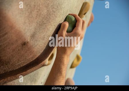 Nahaufnahme der rechten Hand eines jungen Kaukasiers, der den Griff an einer Kletterwand ergreift Stockfoto