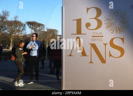 (190331) -- PARIS, 31. März 2019 (Xinhua) -- Touristen stehen an einem Brett, das den 130. Jahrestag des Eiffelturms in Paris, Frankreich, am 30. März 2019 feiert. Eine Reihe von Veranstaltungen, darunter Aufführungen, Fotoshows und Abenteuerspiele, werden ab März 30 stattfinden, um das 130-jährige Bestehen des Eiffelturms zu feiern. (Xinhua/Gao Jing) FRANKREICH-PARIS-EIFFELTURM-130 Jahre PUBLICATIONxNOTxINxCHN Stockfoto