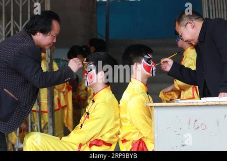 (190402) -- JINPING, 2. April 2019 (Xinhua) -- Lehrer malen die Gesichter von Schülern in Vorbereitung auf den Drachentanz an der Longli Mittel- und Grundschule im Jinping County, südwestchinesische Provinz Guizhou, am 20. März 2019. Longlis Drachentanz wurde 2005 als immaterielles Kulturerbe der Provinz Guizhou klassifiziert und hat eine Geschichte von mehr als 600 Jahren. Es zeichnet sich durch das schöne Gesicht der Tänzer aus. Seit 2008 wird Longlis Drachentanz in die Longli Mittel- und Grundschule eingeführt, deren Schüler zwei Stunden pro Woche mit Drachentanzmeistern verbringen, um Kostümmaki zu lernen Stockfoto